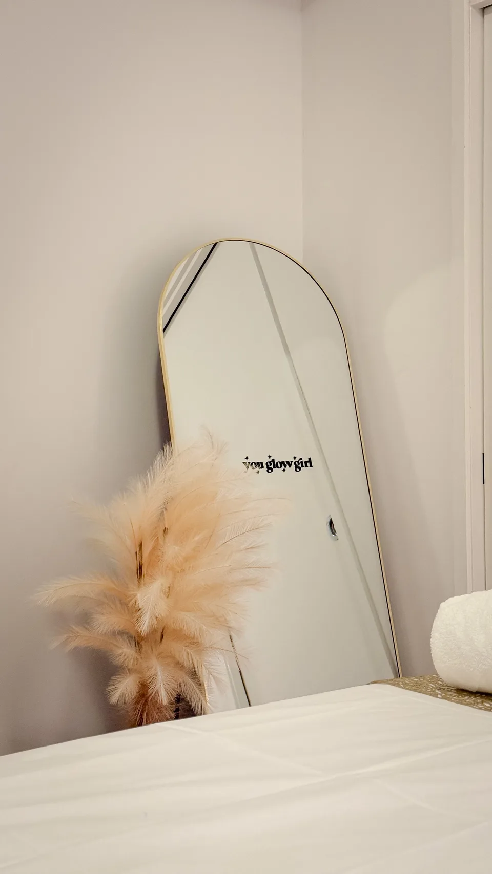 Gold-framed mirror and soft pampas styling beside the Aura Glow treatment bed.