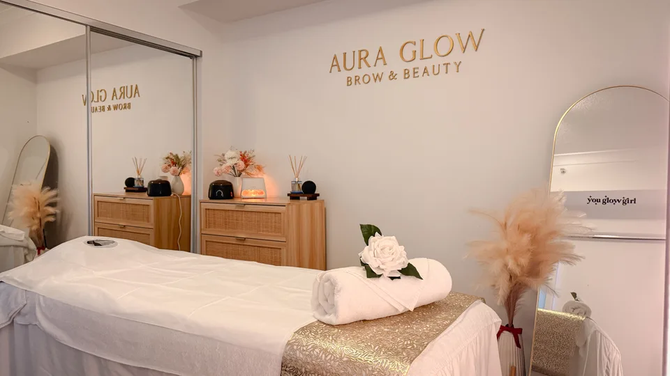 Aura Glow’s private home studio, with a prepared treatment bed, warm timber furniture and gold wall sign.